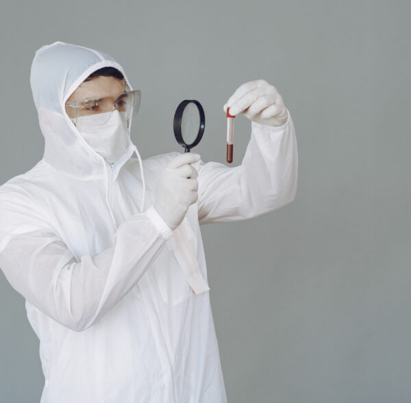 Corona virus theme. Man in a protective suit. Doctor looks at the blood tube.