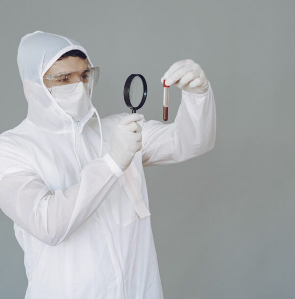 Corona virus theme. Man in a protective suit. Doctor looks at the blood tube.
