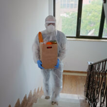 Volunteer delivering food order wearing coverall suit in covid-19 pandemic.